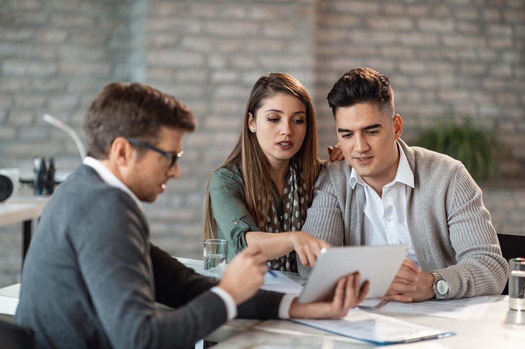 young-couple-using-touchpad-with-insurance-agent-while-making-loan-repayment-plan-meeting_637285-861