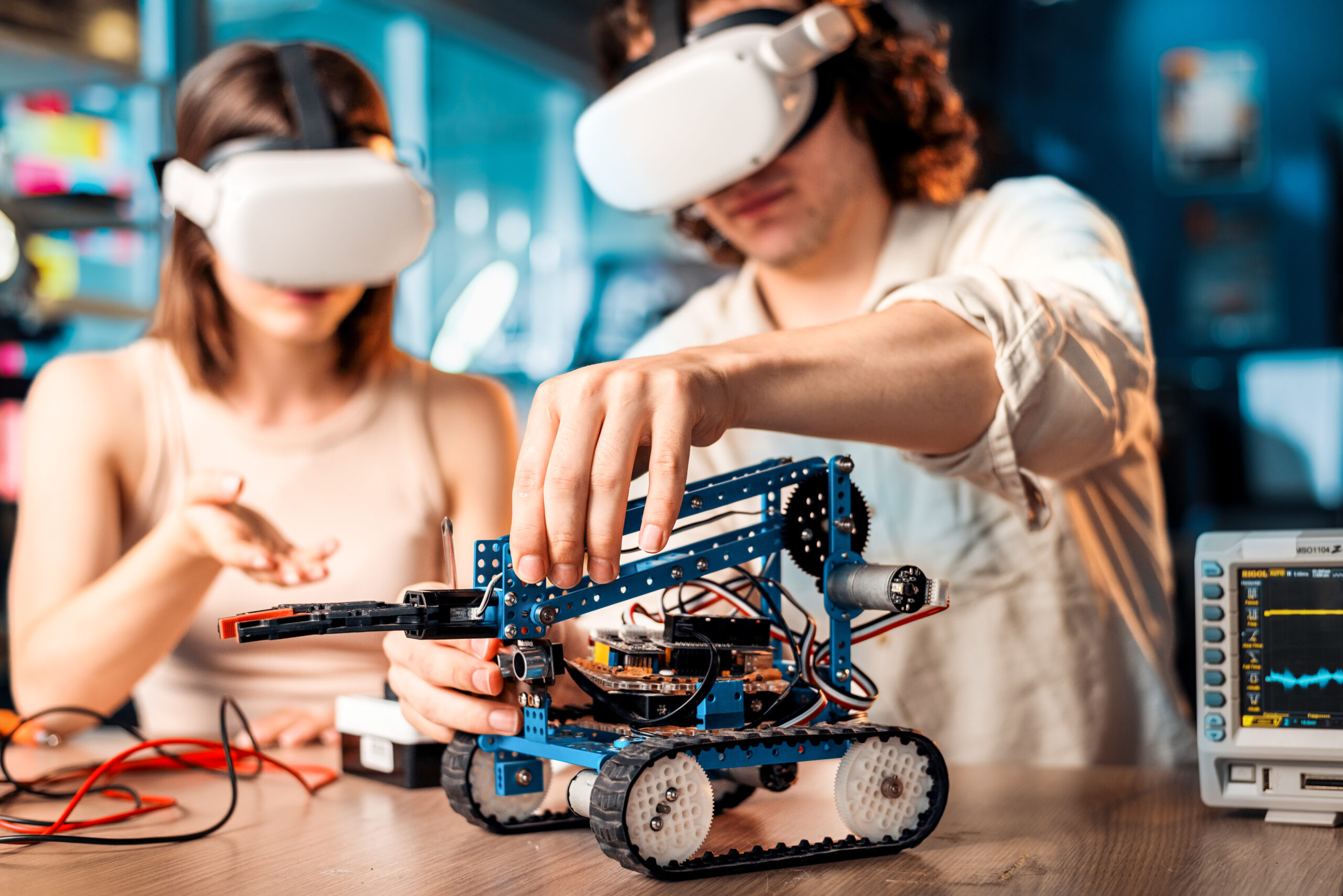 Young man and woman in VR glasses doing experiments in robotics in a laboratory